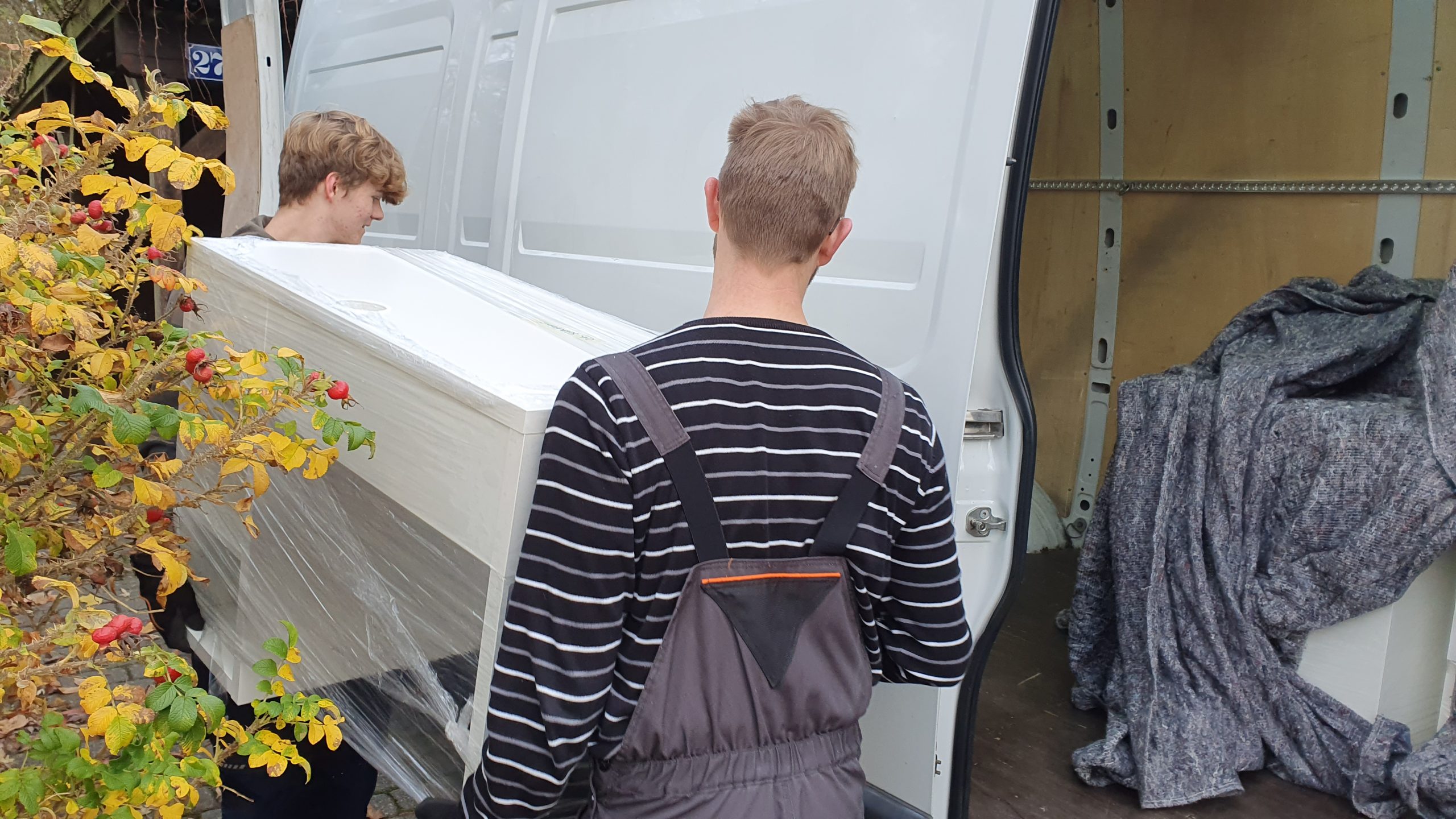 Umzugshelfer transportieren Möbel in einen Umzugswagen.