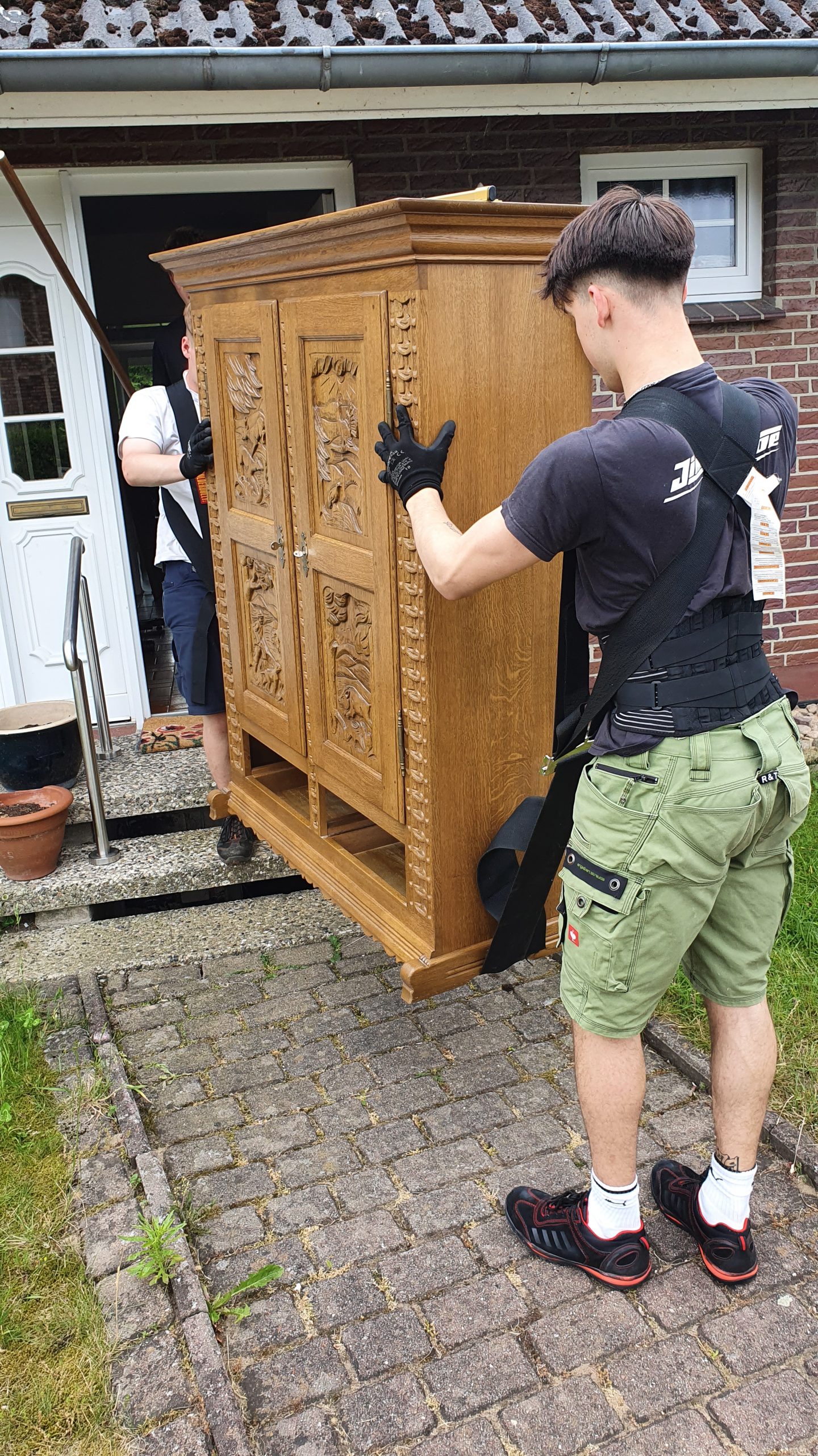 Mitarbeiter von Seniorenumzüge Lüneburg tragen einen Schrank durch eine Tür